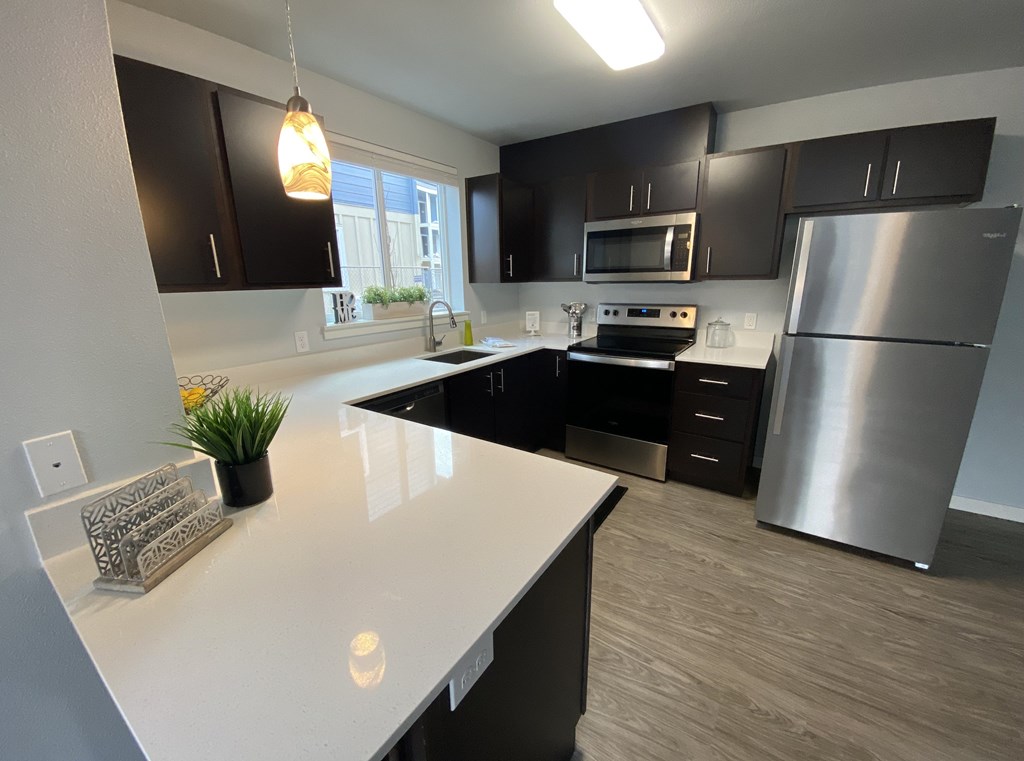 A modern kitchen with a white countertop and stainless steel appliances.