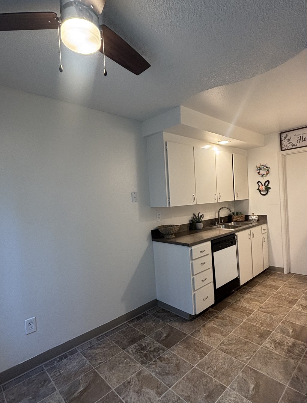 A kitchen with white cabinets and a tile floor.