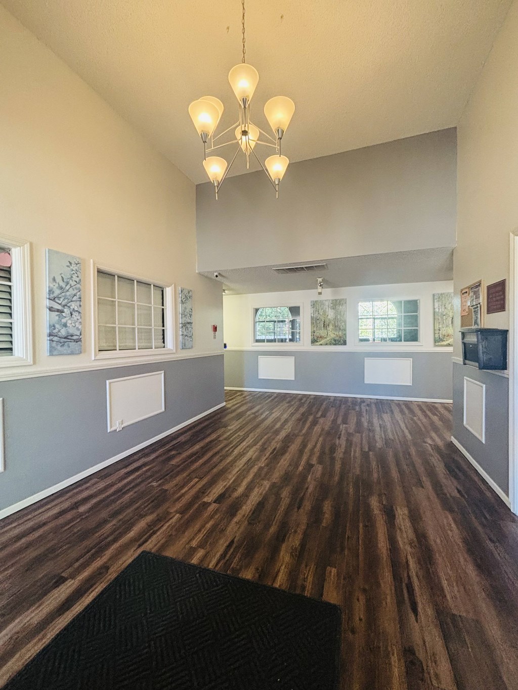 A room with wooden floors and a black rug in the foreground.