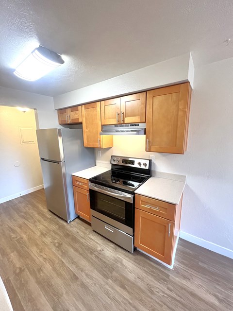 A kitchen with wooden cabinets and a stainless steel refrigerator.