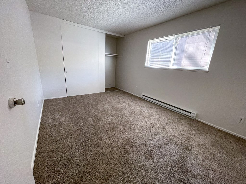 an empty bedroom with a closet and a window