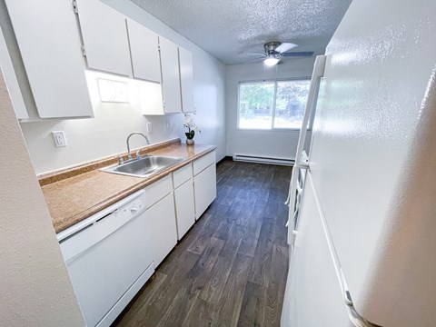 A kitchen with white cabinets and a wooden counter top.