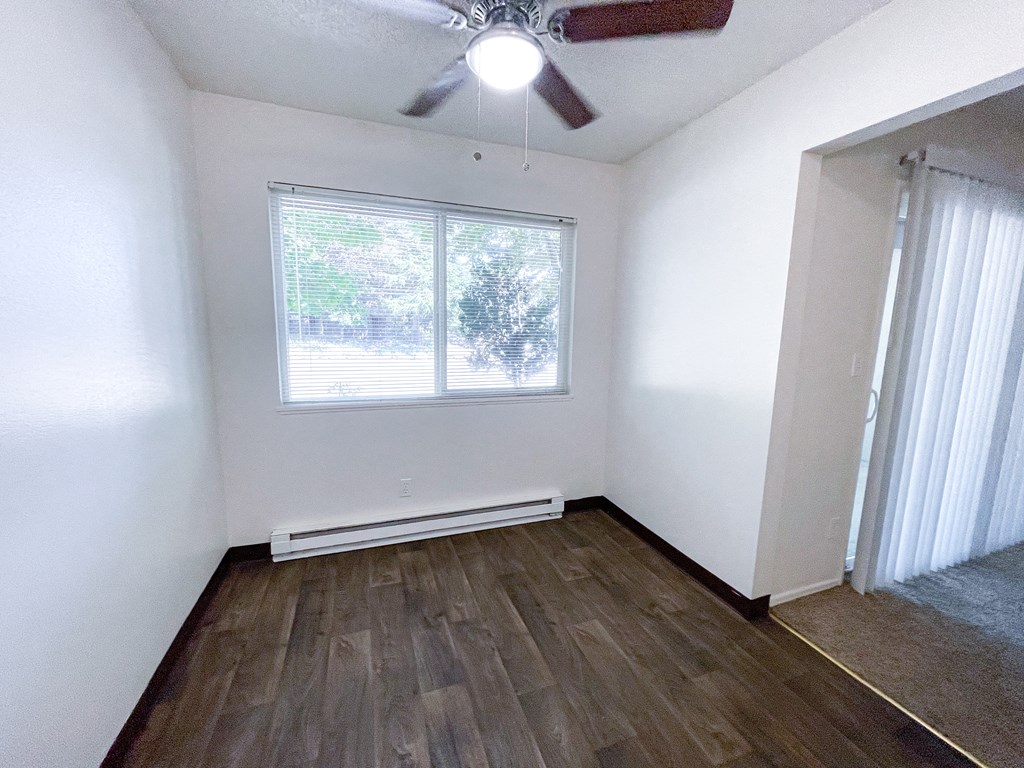 an empty room with a ceiling fan and two windows