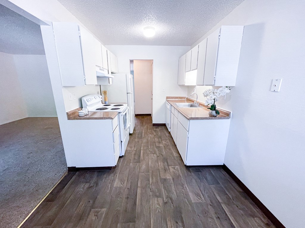 a kitchen with white cabinets and a wooden floor