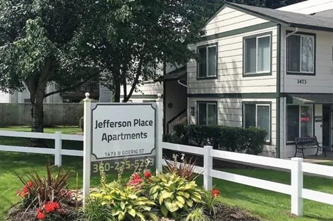 A sign for Jefferson Place Apartments is in front of a building.