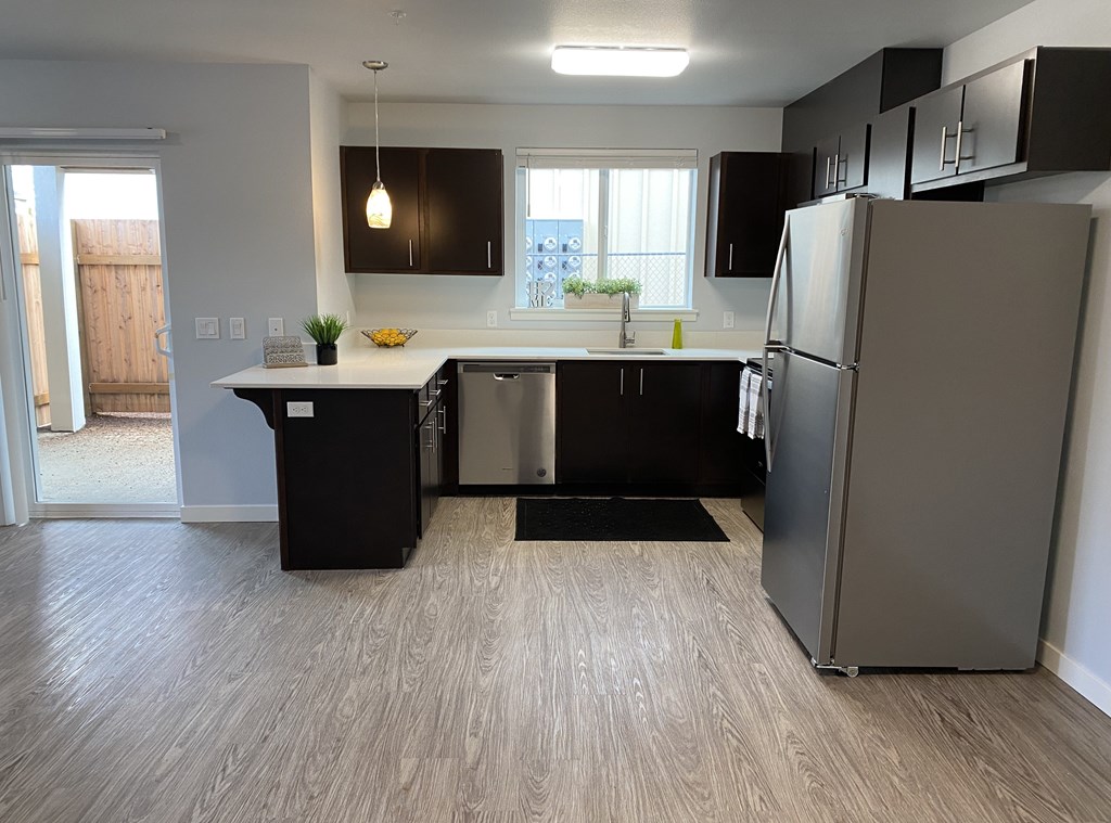 A kitchen with black cabinets and a wooden floor.