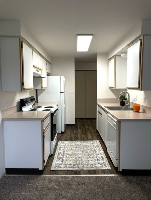 A kitchen with white cabinets and a rug on the floor.