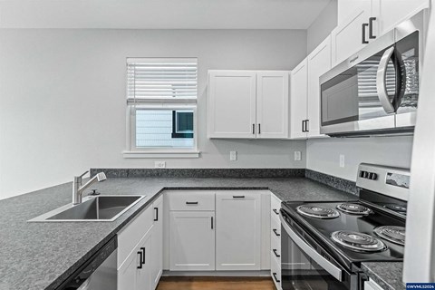 A kitchen with white cabinets and a black stove top.