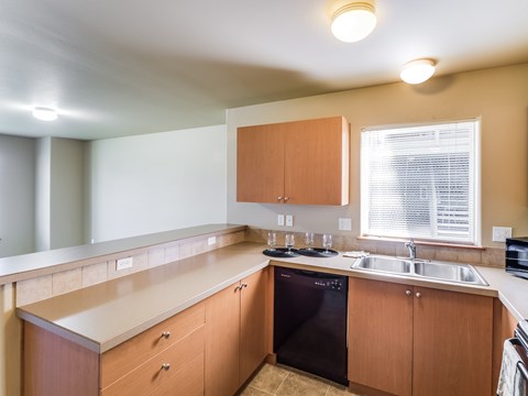 A kitchen with wooden cabinets and a black dishwasher.