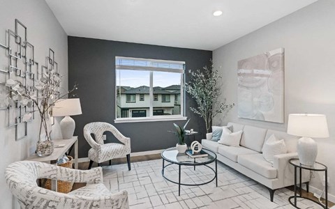 A living room with a white couch, a black coffee table, and a large window.
