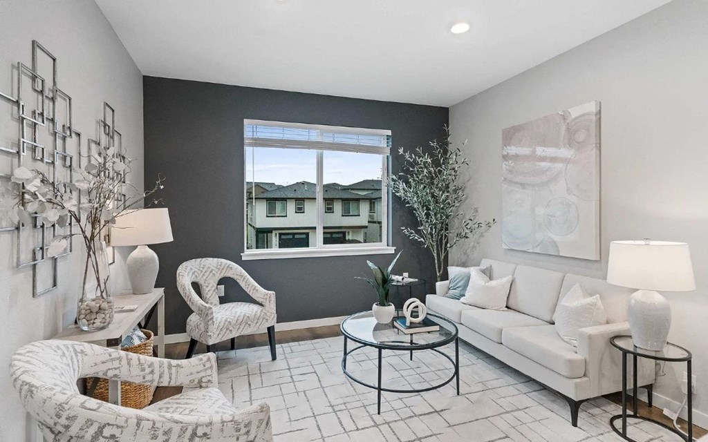 A living room with a white couch, a black coffee table, and a large window.