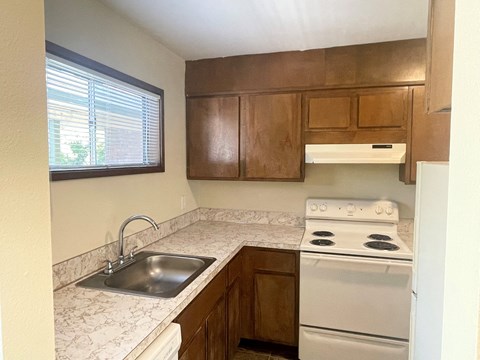 A kitchen with a white stove and wooden cabinets.