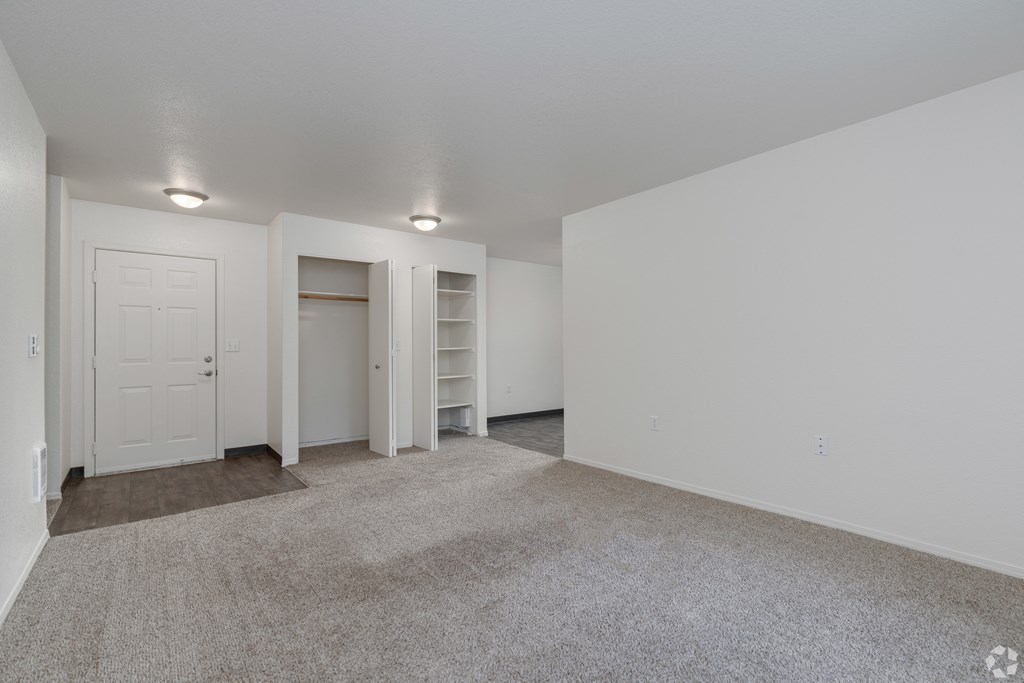 A large, empty room with a carpeted floor and white walls.