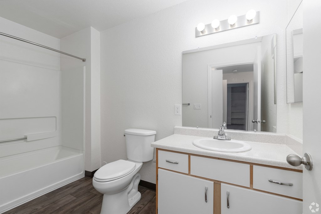 A white bathroom with a toilet, sink, and mirror.