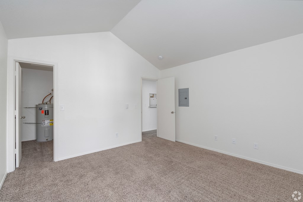 A spacious room with white walls and carpeted floor.
