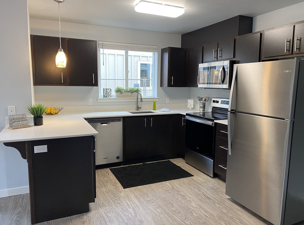 A modern kitchen with black cabinets and stainless steel appliances.