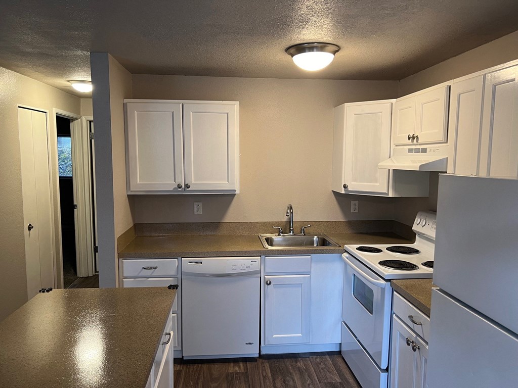 a kitchen with white cabinets and white appliances and counter tops