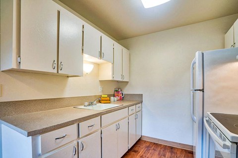 a kitchen with white cabinets and a sink and a refrigerator