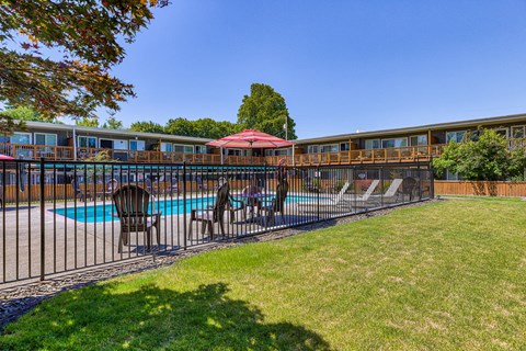 a yard with a pool and chairs and a fence