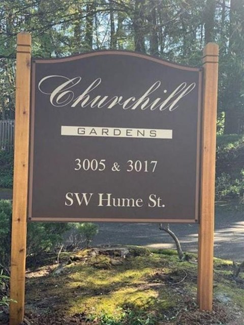 a sign for chunchill gardens with trees in the background