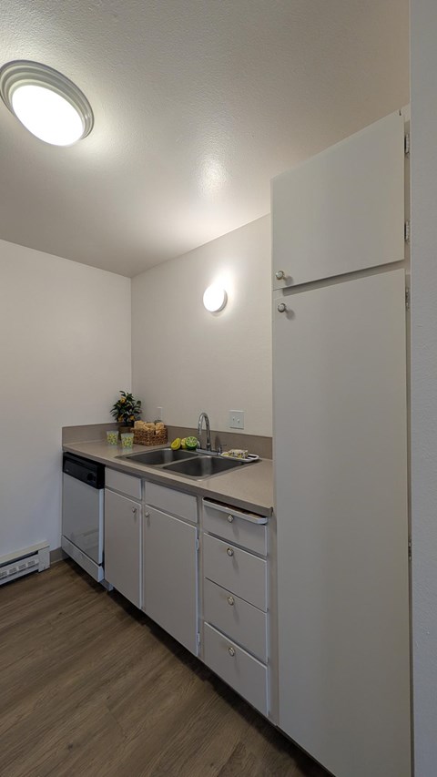 A kitchen with white cabinets and a white refrigerator.