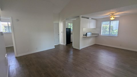 A spacious living room with hardwood floors and white walls.