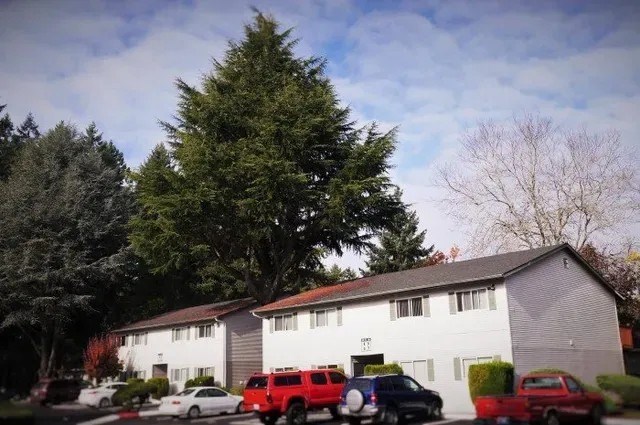 A white house with a red car in front.