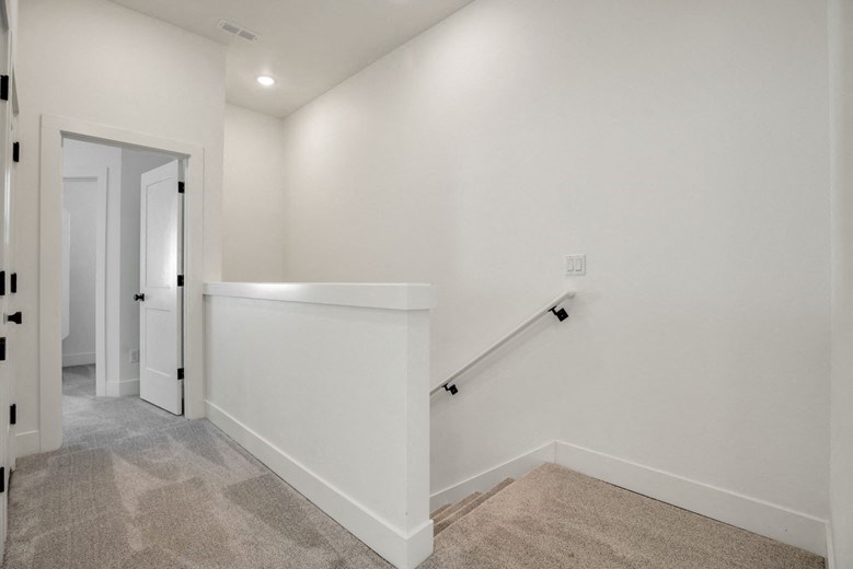 the landing of a home with a staircase and white walls