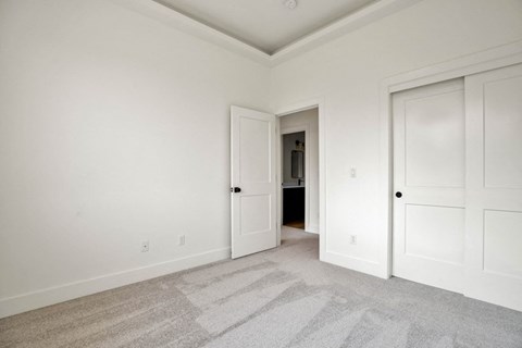 an empty bedroom with two doors and a carpeted floor