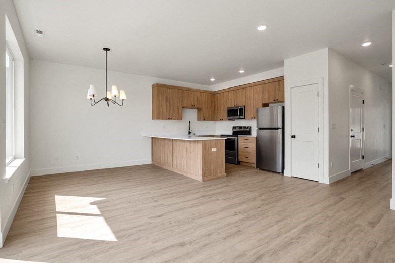 an empty kitchen with wood flooring and a stainless steel refrigerator