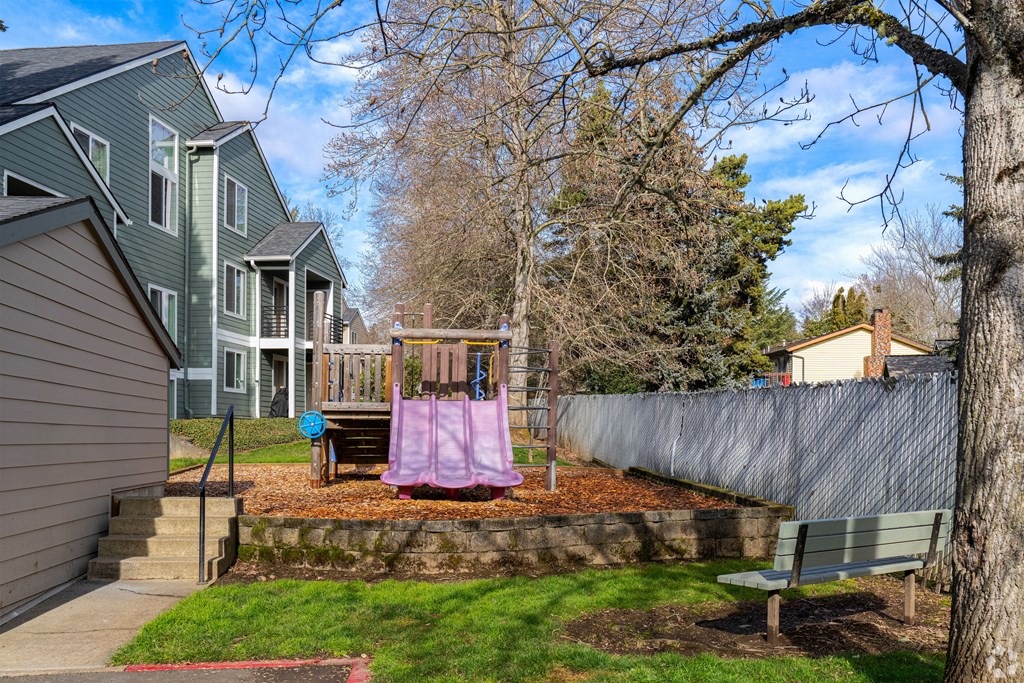 A backyard with a swing set and a fence.