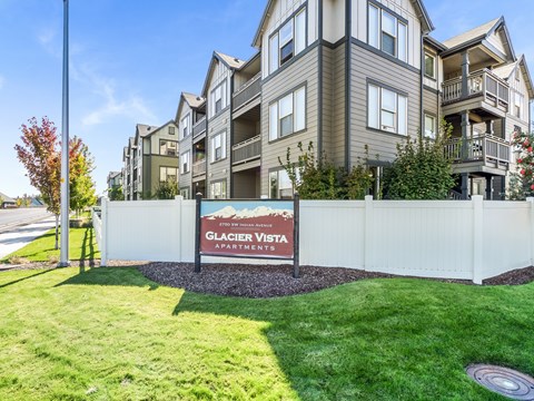 A sign for Glacier Vista Apartments is in front of a building.