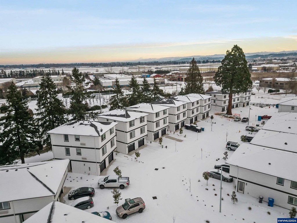 A snowy landscape with apartment buildings and cars.