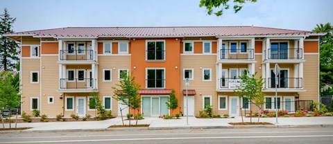 Apartment building with balconies and a red awning.