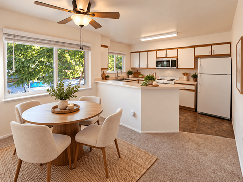 A kitchen with a table and chairs in the foreground and a refrigerator in the background.