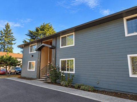 A grey house with a brown door and windows.