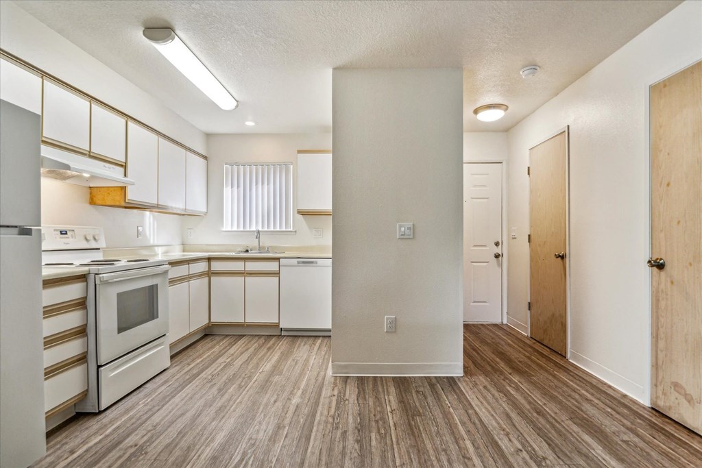 a renovated kitchen with white cabinets and appliances and wood flooring