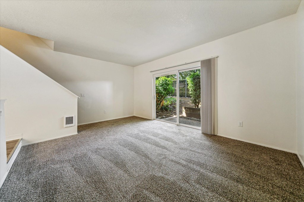a living room with carpet and a sliding glass door to a patio