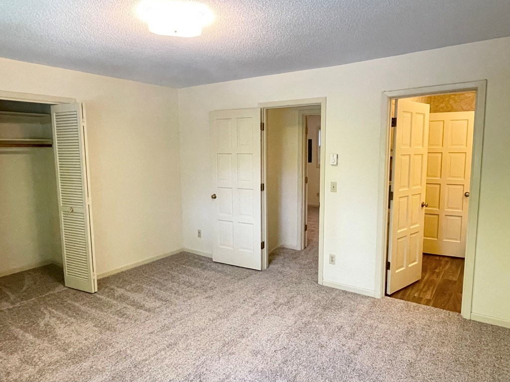 a bedroom with a carpeted floor and a closet with a door open