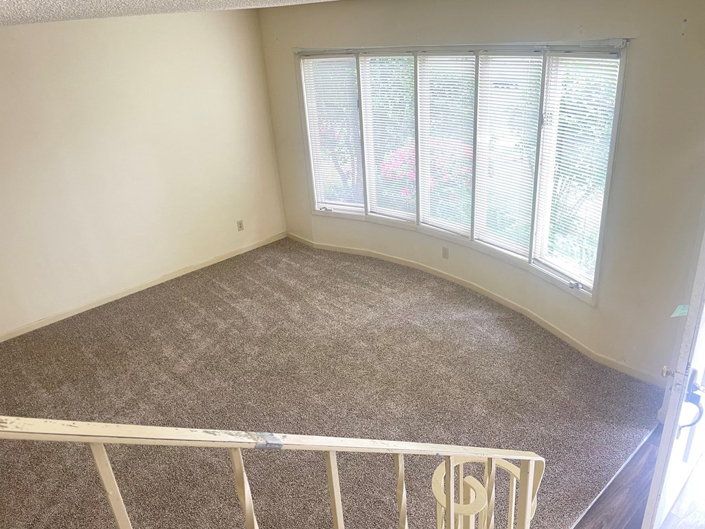 an empty room with a large window and a crib in the corner