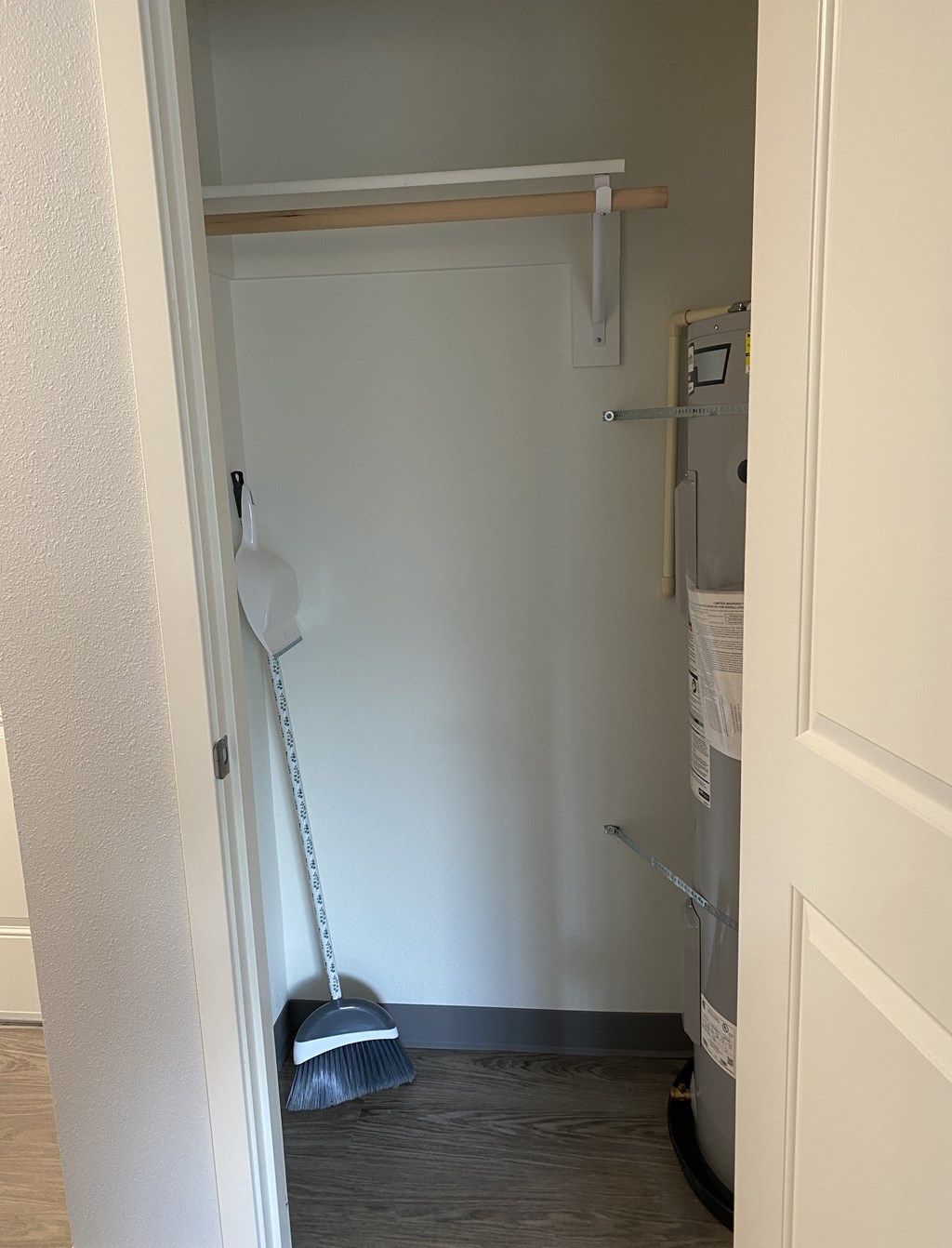 A white closet with a broom and a mop.