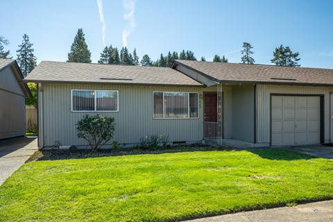 A house with a garage and a small tree in the front yard.