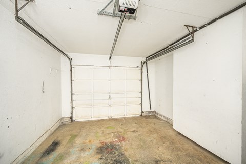 A white garage door is closed and there is a white wall on the left side of the garage.