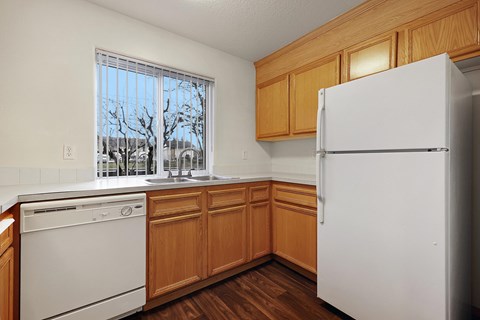 A kitchen with a white fridge, dishwasher and wooden cabinets.