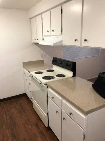 A kitchen with white cabinets and a stove top oven.