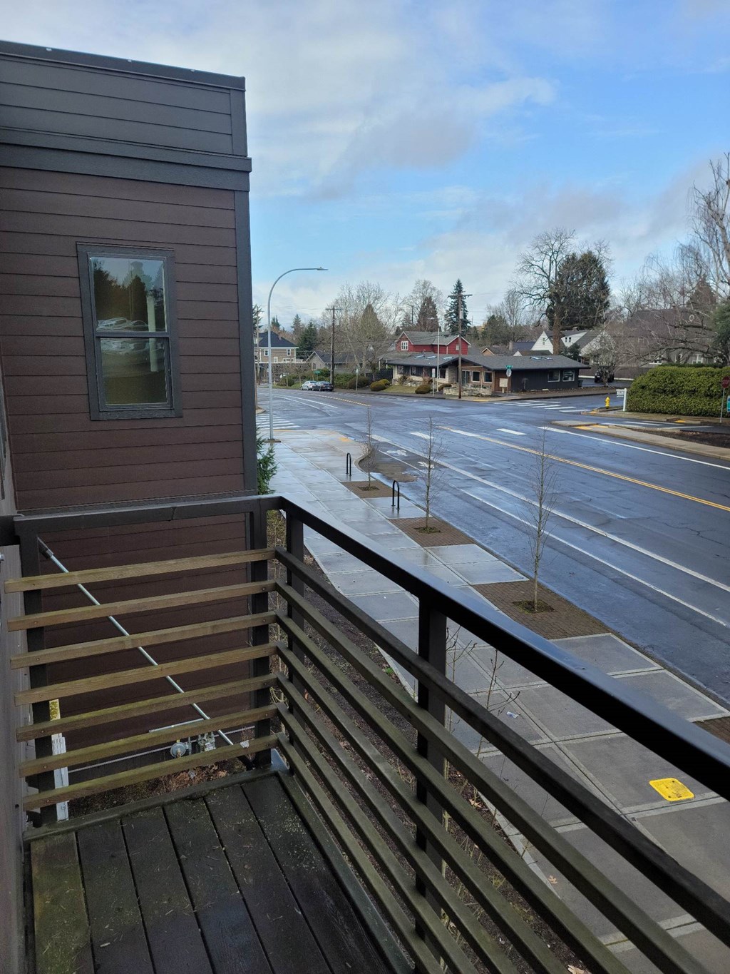 A view from a balcony overlooking a street with a building in the distance. Clark Apartments Vancouver WA