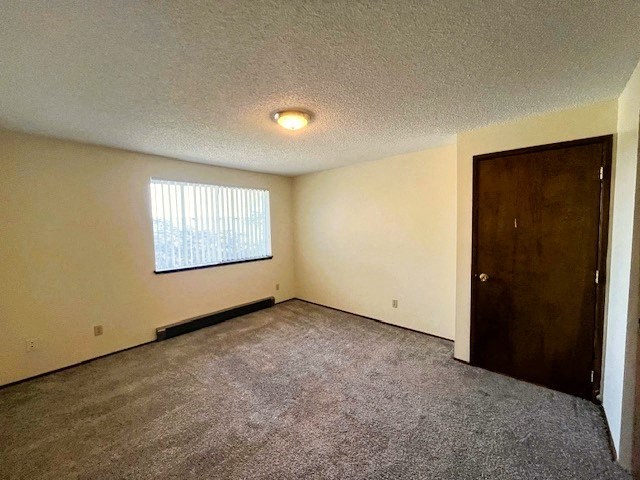 A room with a carpeted floor, a window with blinds, and a closed door.