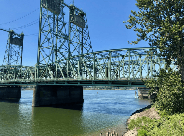 A metal bridge spans over a body of water. Clark Apartments Vancouver WA