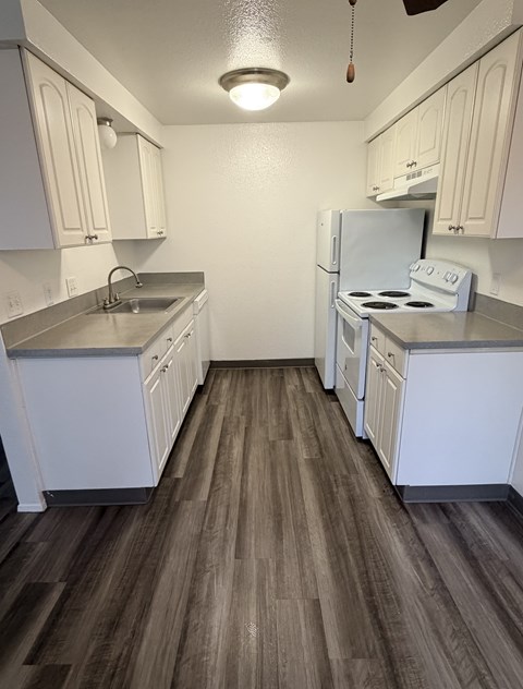 A kitchen with white cabinets and a white refrigerator.
