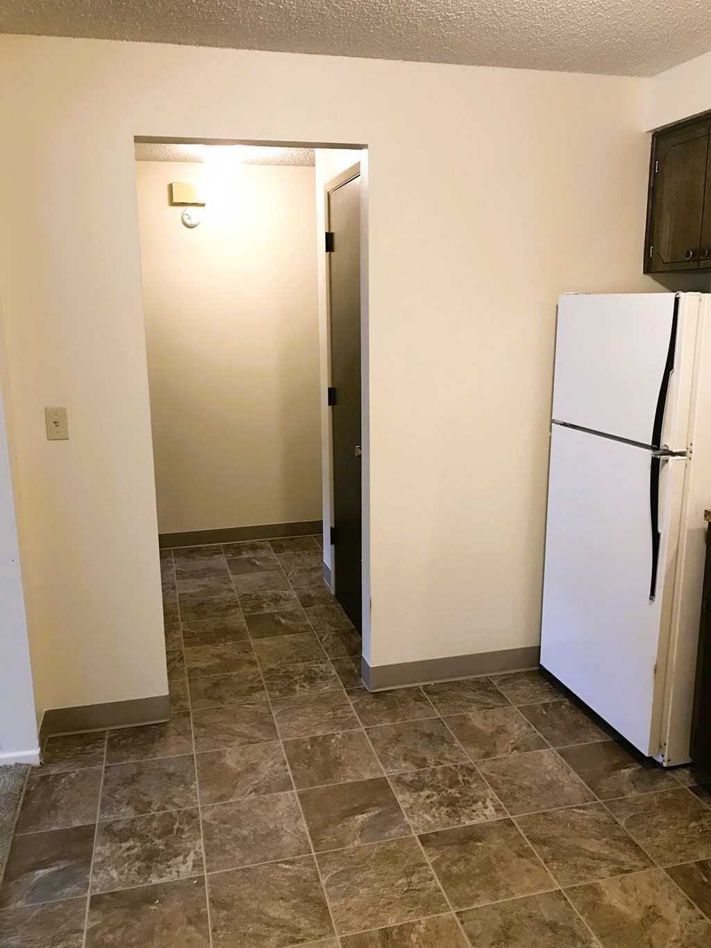 Nell Anna Court white refrigerator sits in a kitchen next to a door.